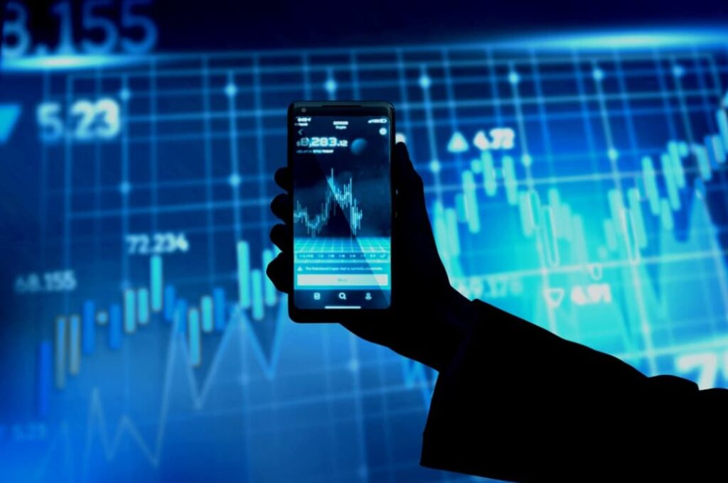 Hand holding a smartphone with stock market data onscreen